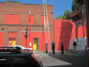 The red fire truck and yellow helmets of the firemen against this building!